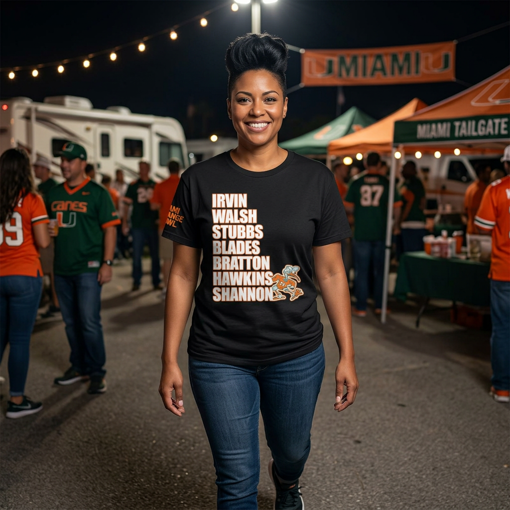 Woman wearing a black t-shirt with text and graphics, standing in a tailgate party setting.1987 UM Football, Creators of Swagger, Miami Sports Apparel, Vintage Streetwear, Retro Championship Shirt, Orange Bowl Kid, Urban Aesthetic, Collegiate Graphics, OBK. 